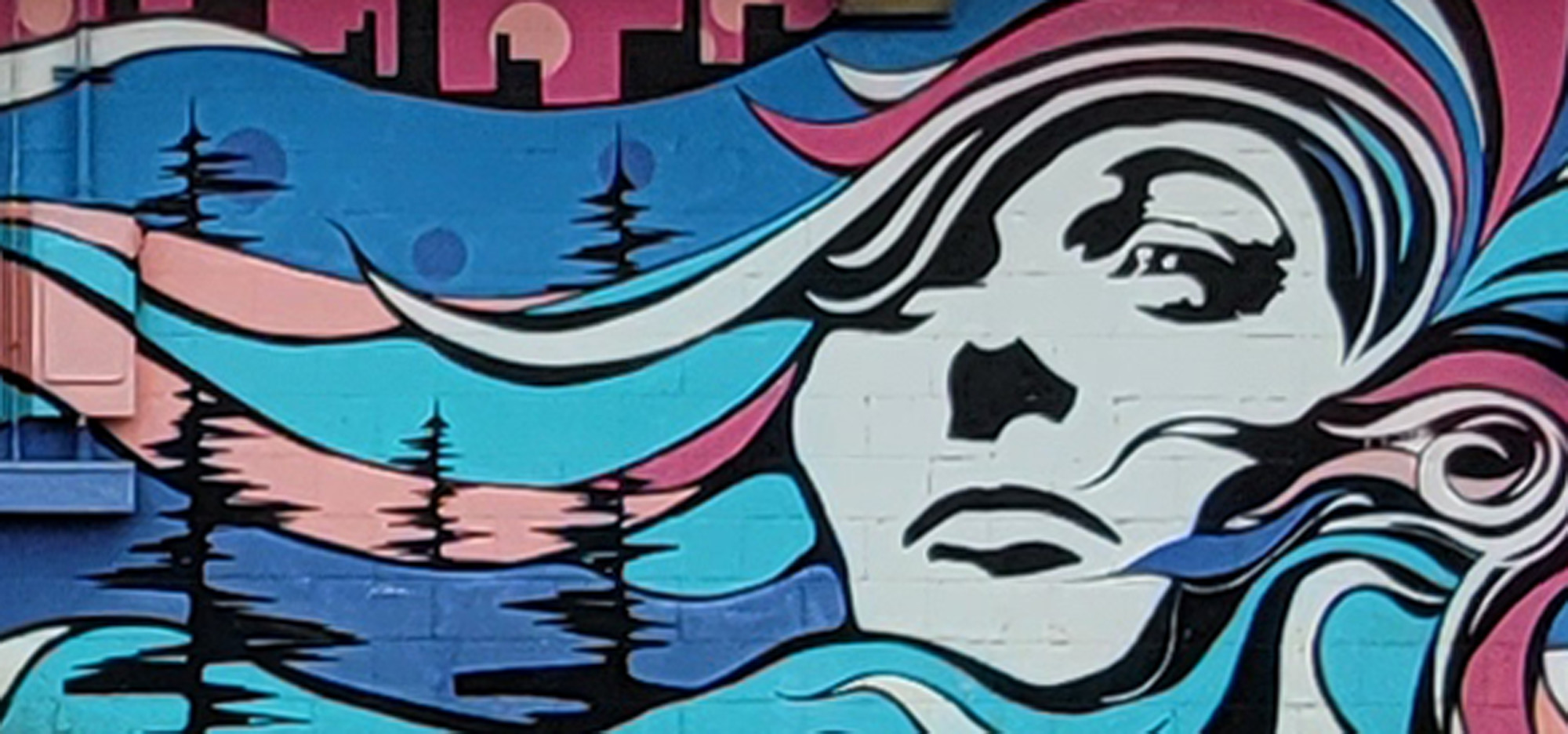 Mural on all of a womans face with bright blues contrasted on striking whites